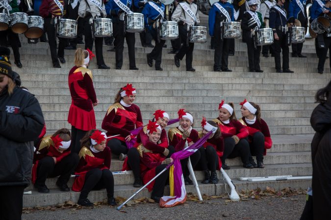 The girls of the AllStars color gaurd have a laugh as they try to stay warm before the start of the 98th annual Philadelphia Thanksgiving Day Parade, November 23, 2017. (Emily Cohen for WHYY)