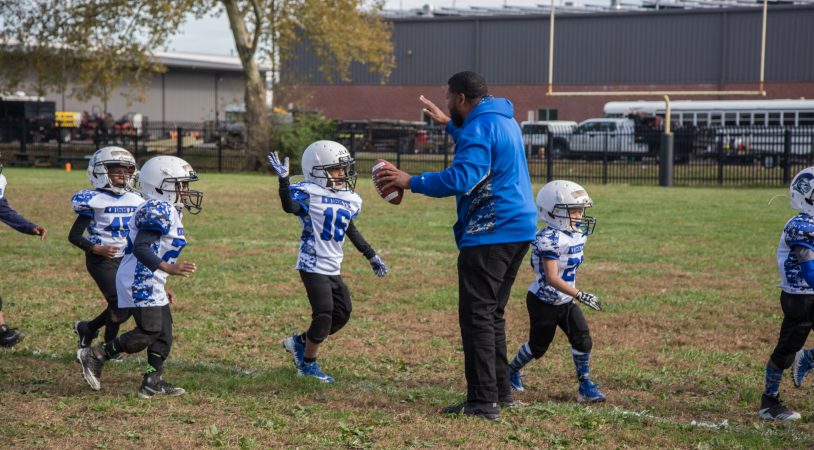 FACT graduate Rickey Duncan high-fives his players as the come off the field for halftime.