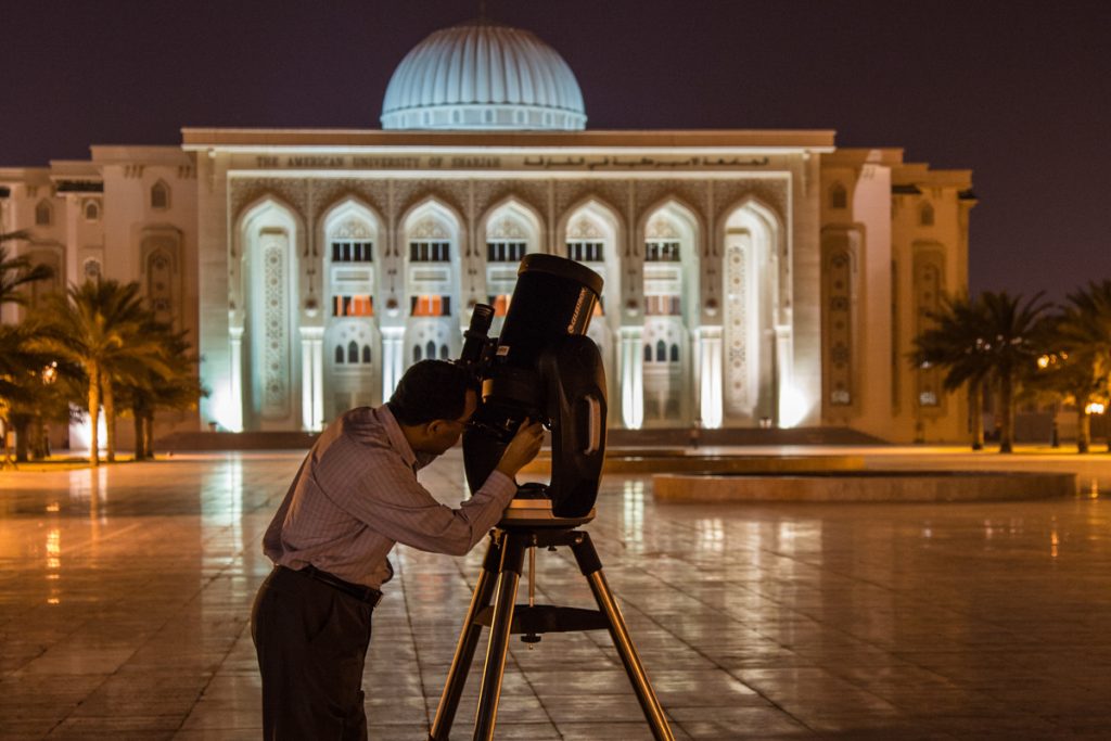 Night Sky man looking through telescope in Middle East