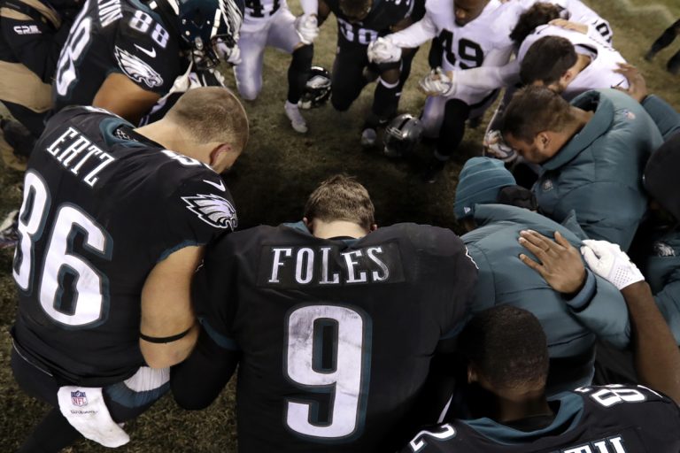 Philadelphia Eagles' Nick Foles (9) kneels with other players after an NFL football game against the Oakland Raiders