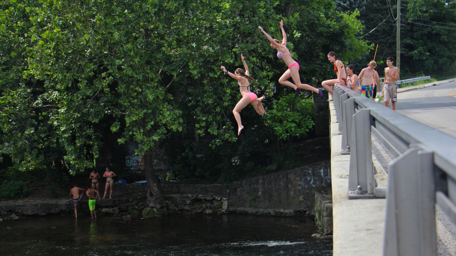 Teenagers take turns jumping into the Musconetcong river just below the Asbury Mill Dam.