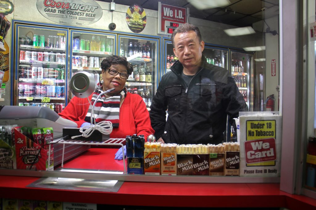 2017 12 11-e lee-o j yoo sylvia combs-philadelphia olney steak and beer-stop and go beer deli Olney Steak and Beer owner O. J. Yoo stands behind a plexiglass window with employee Sylvia Combs.