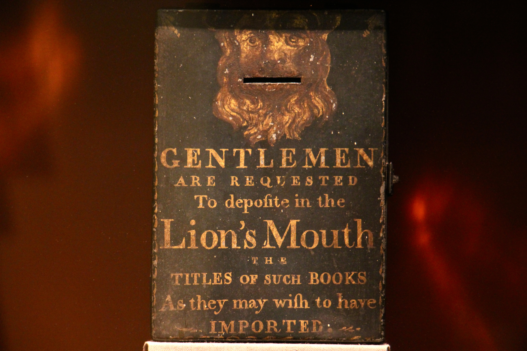 A relic from the early days of Benjamin Franklin's Library Company , a box for requested titles, remains on the shelf behind a layer of plexiglass.