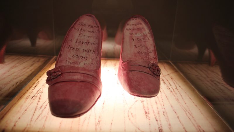 The shoes of Ortiz's grandmother are inscribed with a poem and the signature from her Colombian passport. (Emma Lee/WHYY)