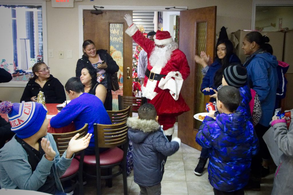 20171223_Holiday_Party_BS1374_013__BAS0699 Santa makes an appearance at a Christmas party for Puerto Rican families at the office of Association of Puerto Ricans In March, on Philadelphia Saturday, for about 20 families displaced from Puerto Rico after hurricane Maria. (Bastiaan Slabbers for WHYY)