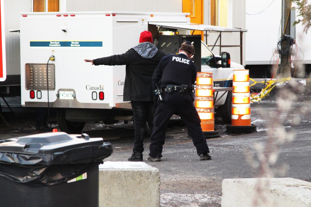 A man from Congo is frisked by Royal Canadian Mounted Police officers after illegally entering Canada, near the border with Champlain, N.Y. A man from Congo is frisked by Royal Canadian Mounted Police officers after illegally entering Canada, near the border with Champlain, N.Y. (Lorne Matalon)
