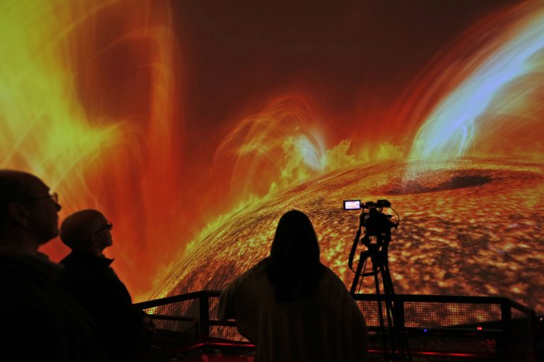 In this Wednesday, Dec. 6, 2017 photo, people watch interstellar bodies move through space during a media preview at the planetarium at Liberty Science Center in Jersey City, N.J. The  newly refurbished planetarium is the largest in the western hemisphere and uses ten advanced projectors to produce an 8K resolution. It opens to the public on Saturday, Dec. 9, 2017. (Seth Wenig/AP Photo)