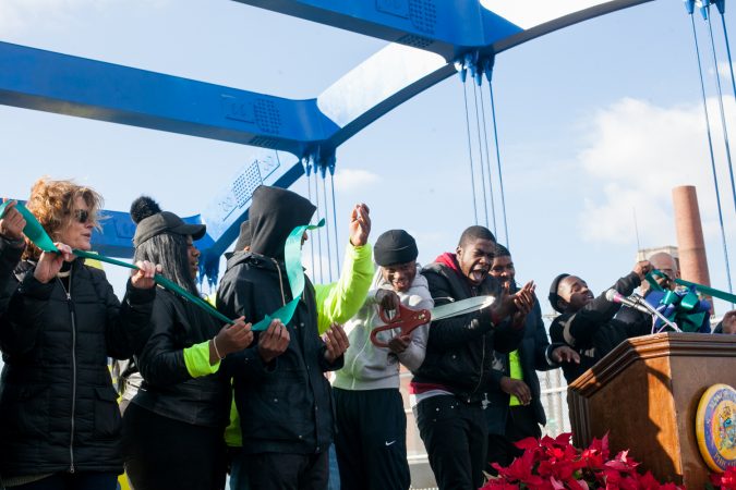 Members of the Youth Violence Reduction Parternship Guild who worked on the new mural on the B Street Bridge in Kensington cut the ribbon at the end of a dedication ceremony Tuesday. (Brad Larrison for WHYY)