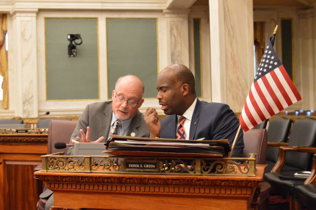 Councilmen Bill Greenlee (left) and Derek Green talk business during a hearing Monday.