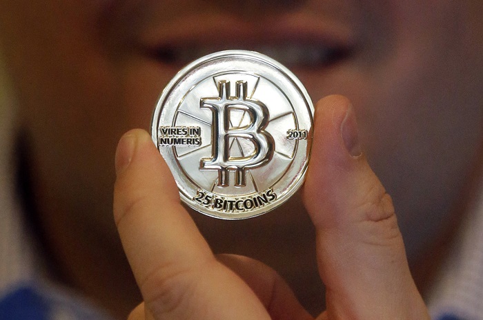Venezuela Bitcoin Boom FILE - In this April 3, 2013 file photo, Mike Caldwell, a 35-year-old software engineer, holds a 25 Bitcoin token at his shop in Sandy, Utah. As Venezuela’s national currency loses value at a catastrophic rate, thousands have begun turning to the world of cryptocurrency to salvage what little value remains from their increasingly worthless bolivars. (AP Photo/Rick Bowmer, File)