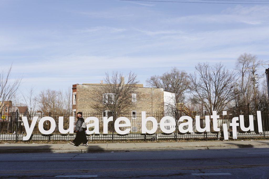 People are seen walking past the “You Are Beautiful” sign, an art installation by Matthew Hoffman, in the Englewood neighborhood on Chicago’s South Side. Nearly half of the people in this African-American neighborhood live below the poverty line, and many seniors have no idea there are public services that might help them. People are seen walking past the