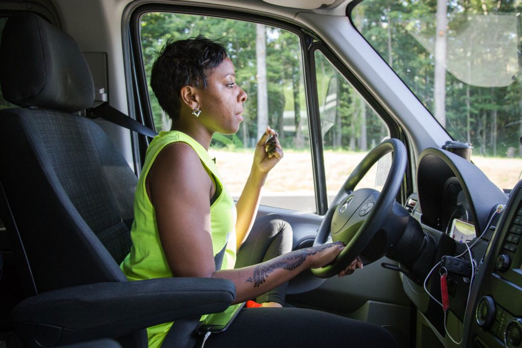 ©KatzSeville_WomenontheOutside_01 Kristal Bush chews on sunflower seeds to keep alert on the long drive to Huntingdon, Pennsylvania. Bush is the founder of @BridgingTheGapLLC transportation company. Several times a week, her vans pick up riders from their homes throughout Philadelphia and drive them to see loved ones in prisons across the state.