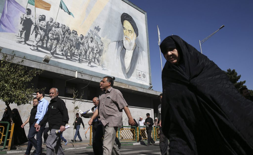 Iran Economic Outcry Iranian worshippers walk past a painting of the late revolutionary founder Ayatollah Khomeini and Basij paramilitary force members, at the conclusion of a Friday prayer ceremony in Tehran, Iran, Friday, Oct. 13, 2017. (Vahid Salemi/AP Photo)