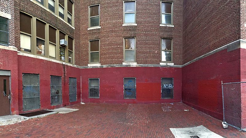 The barred first-floor windows in the courtyard at McClure School before they were brightened by the paintings of parent and teaching artist Carlos Aviles.