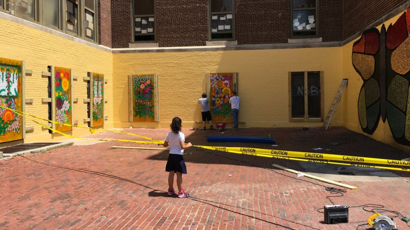 A student watches as paintings are installed in the McClure School courtyard.