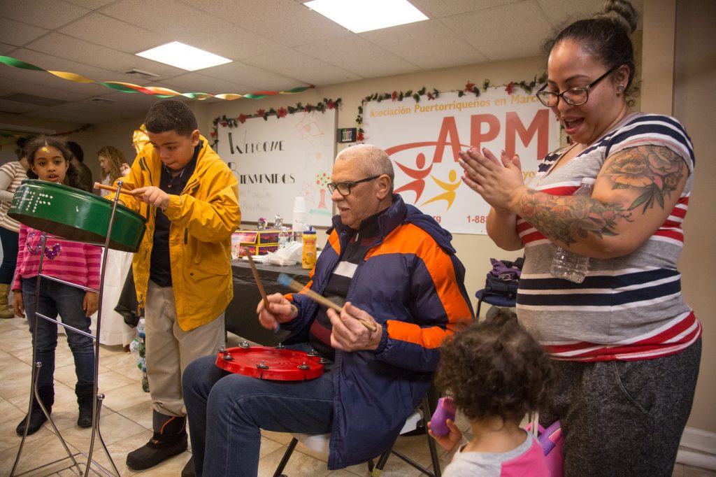 cohen_3kingscelebration-11 Asaf Barrios, 11, jams out on his steele drum accompanied by his father, Raul, at APM's Three Kings Day/Octavious celebration for displaced families from Puerto Rico in North Philadelphia on January 12 2018. (Emily Cohen for WHYY)