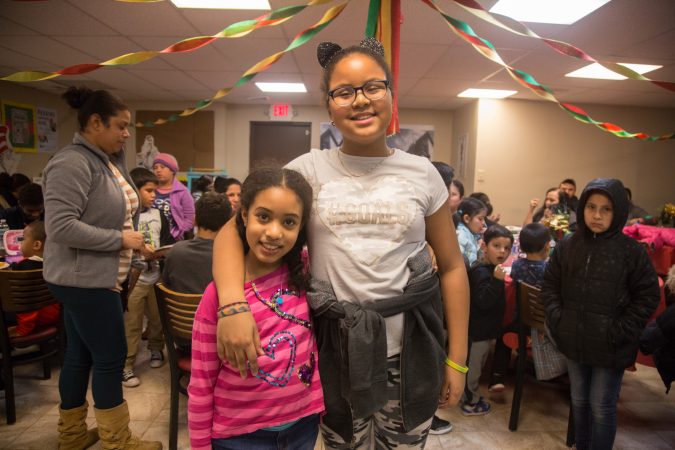 Sisters Layla, 8, (left) and Lia, 11, pose for a photo at APM's Three Kings Day/Octavious celebration for diplaced families from Puerto Rico in North Philadelphia on January 12 2018. (Emily Cohen for WHYY)