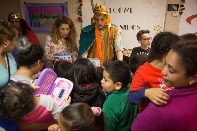 Tom Diagostino passes out gifts as one of the three kings to the children at the celebration. APM threw a Three Kings Day/Octavious celebration for diplaced families from Puerto Rico in North Philadelphia on January 12 2018. (Emily Cohen for WHYY)