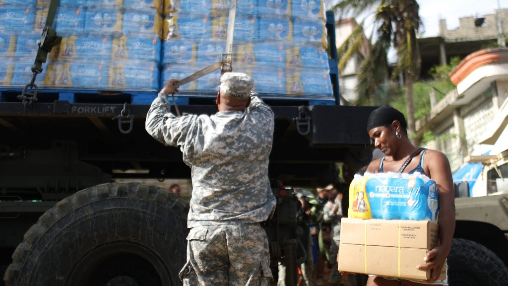 A U.S. Army soldier unloads a shipment of water provided by FEMA as a resident walks past in San Isidro, Puerto Rico. A U.S. Army soldier unloads a shipment of water provided by FEMA as a resident walks past in San Isidro, Puerto Rico