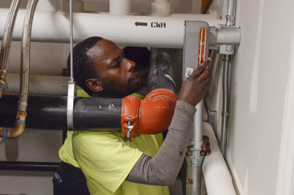 012918-solar-installation Richard Tumushime, an electrician with Pittsburgh-based Energy Independent Solutions, works with a crew to put the finishing touches on wiring a solar panel system at the new Forest Hills Municipal Building. (Amy Sisk/StateImpact Pennsylvania)