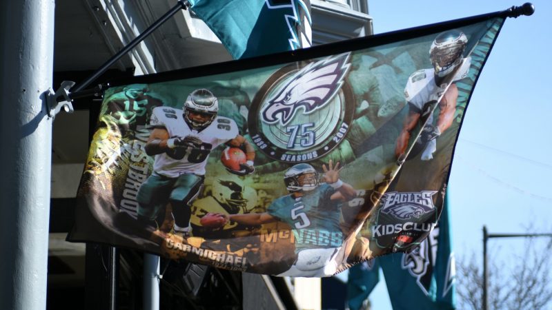 Flags in support of the Philadelphia Eagles hang above a bar in Manayunk on Wednesday. The banner harkens back to the Eagles 75th anniversary season in 2007, when the team compiled an 8–8 record and a last-place finish in the NFC East. (Bastiaan Slabbers for WHYY)