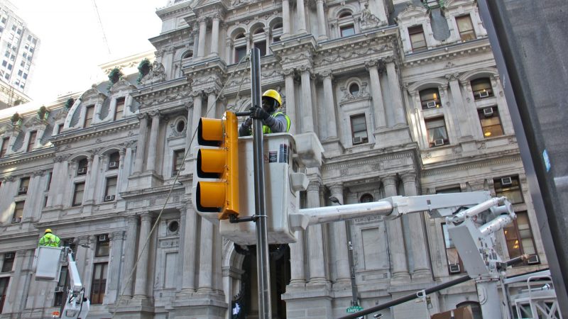 Workers replace the traffic lights on Market Street east of City Hall after celebrating Eagles fans tore them down. (Emma Lee/WHYY)