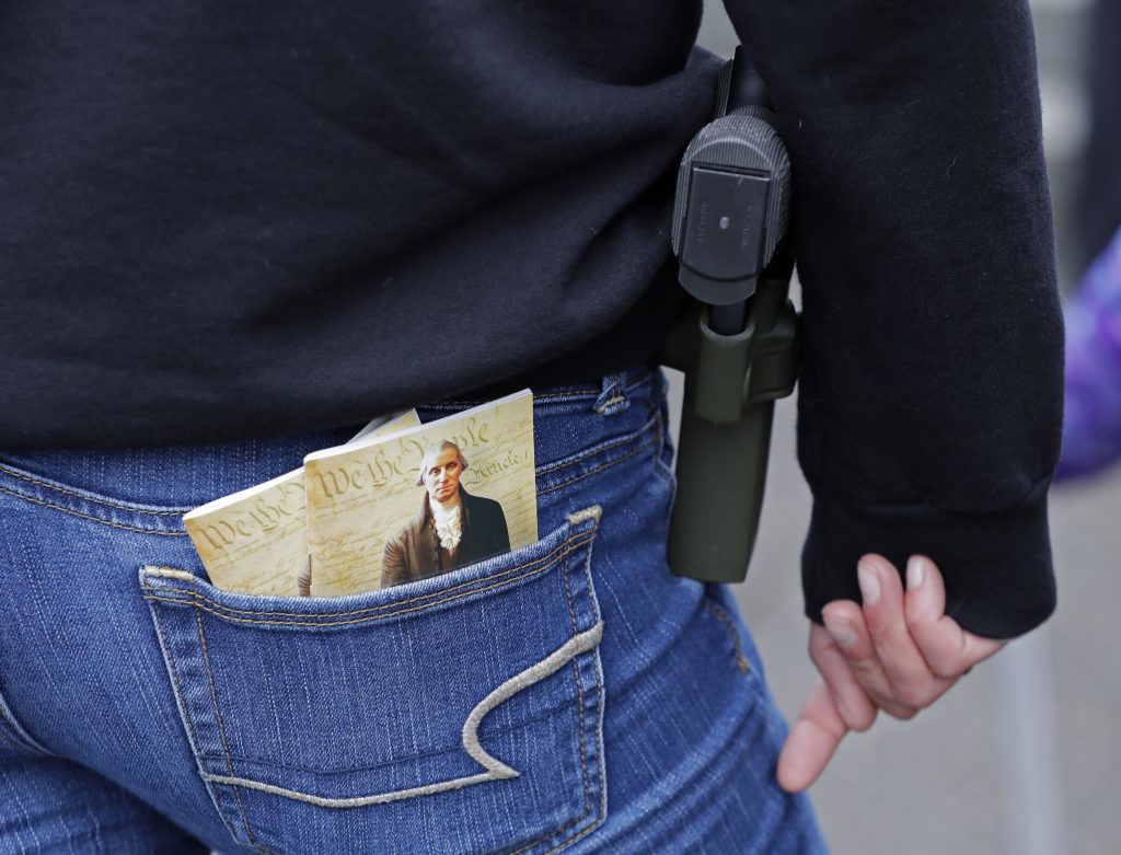 Gun Control In this Jan. 12, 2018 photo, a woman wears a gun in a holster next to two copies of the U.S. Constitution during a gun rights rally at the Capitol in Olympia, Wash.