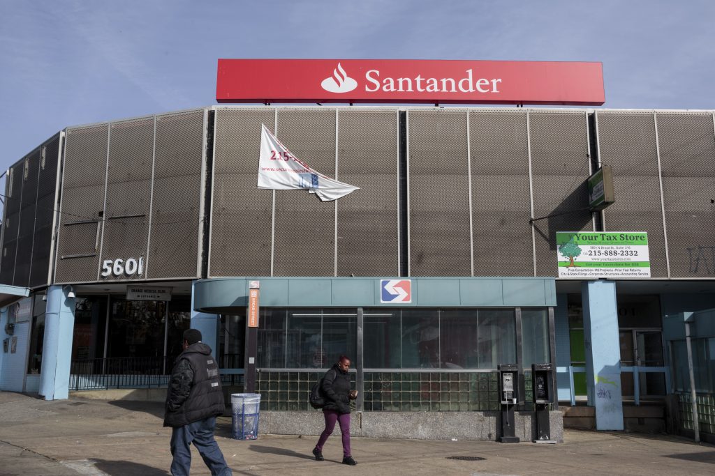 Reveal Modern Day Redlining pedestrians pass a now-closed Santander Bank branch in Philadelphia.
