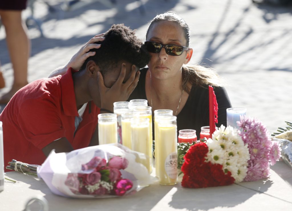 Che James-Riley, Pamela Tilton Pamela Tilton, (right), comforts Che James-Riley, 18, as they light a candle at a memorial for the victims of the shooting at Marjory Stoneman Douglas High School, Thursday, Feb. 15, 2018, in Parkland, Fla. (Wilfredo Lee/AP Photo)