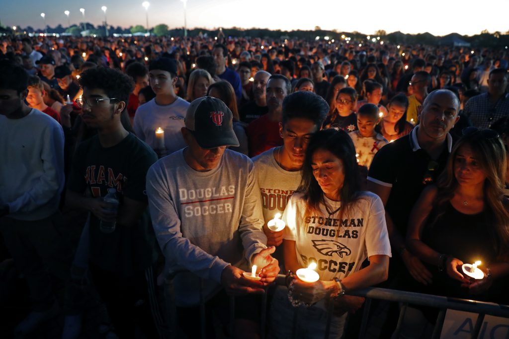 School Shooting Florida Jorge Zapata, Jr., center, a student at Marjory Stoneman Douglas High School, holds candles with his mother Lavinia Zapata, and father Jorge Zapata, Sr., during a candlelight vigil for the victims of the Wednesday shooting at the school, in Parkland, Fla., Thursd