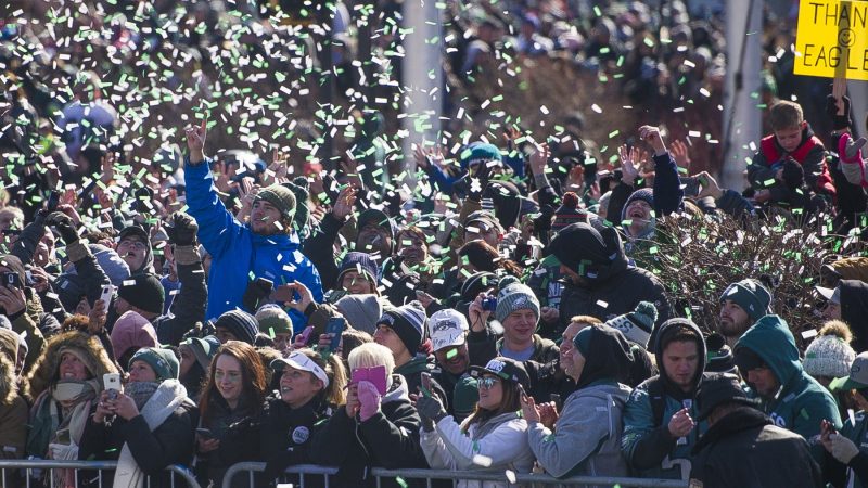 Fans are showered with confetti from passing team buses. (Jonathan Wilson for WHYY)