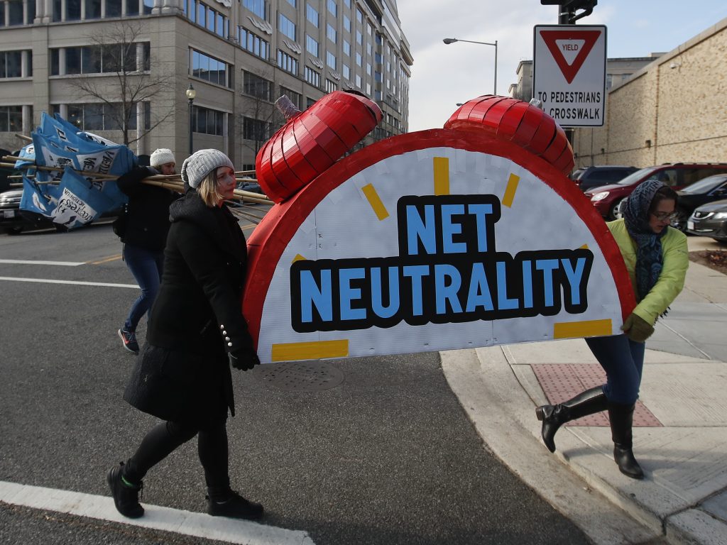 Protesters Sammi LeMaster and Katherine Fuchs carry the top of an alarm clock display that reads “Net Neutrality” after a demonstration at the Federal Communications Commission on Dec. 14, 2017. Protesters Sammi LeMaster and Katherine Fuchs carry the top of an alarm clock display that reads
