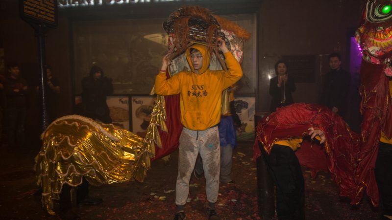 A member of the Philly Suns takes off his lion head after a sucessful lion dance through the streets of Chinatown in celebration of the Chinese New Year on February 15, 2018. (Emily Cohen for WHYY)