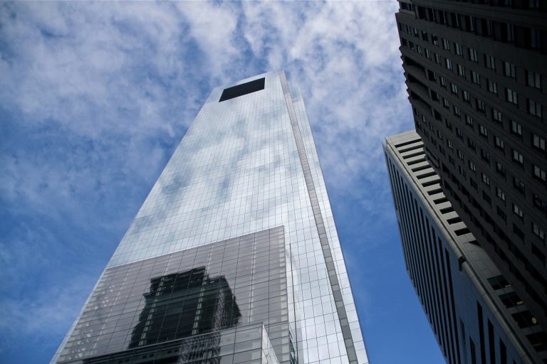 The Comcast tower in Philadelphia reflects clouds and blue sky.