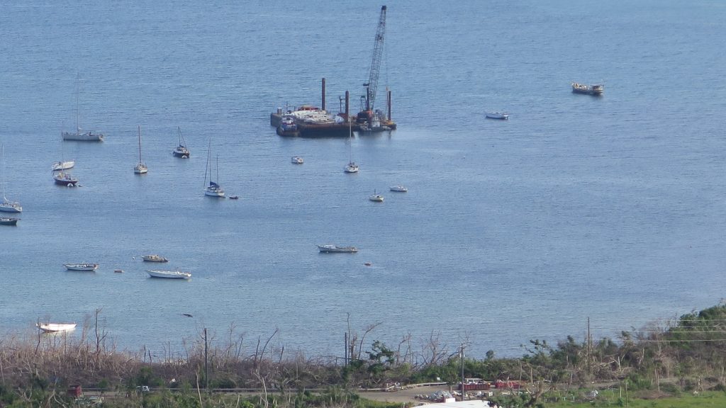 Coral Bay, on the eastern end of St. John, is home to an active sailing community. For months, the Coast Guard has been using a crane boat and barge to retrieve sunken vessels. Coral Bay, on the eastern end of St. John, is home to an active sailing community. For months, the Coast Guard has been using a crane boat and barge to retrieve sunken vessels. (Greg Allen/NPR)