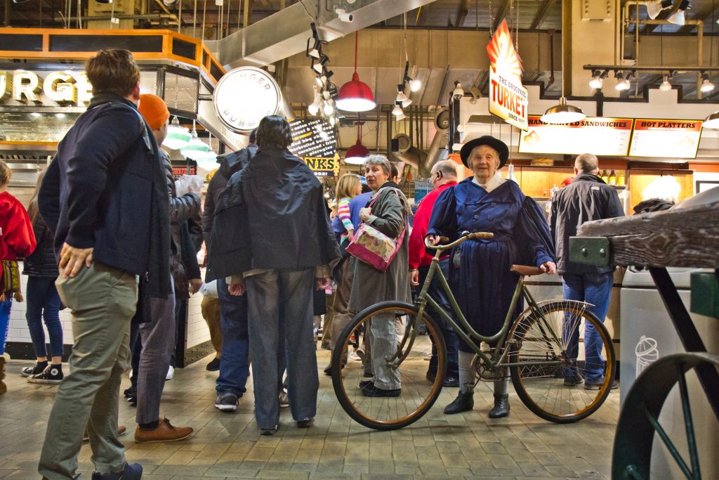 Sue Gray of the Wheelman Antique Bike Club shows off her bike at the Reading Terminal Market 125th anniversary celebration. (Kimberly Paynter/WHYY)