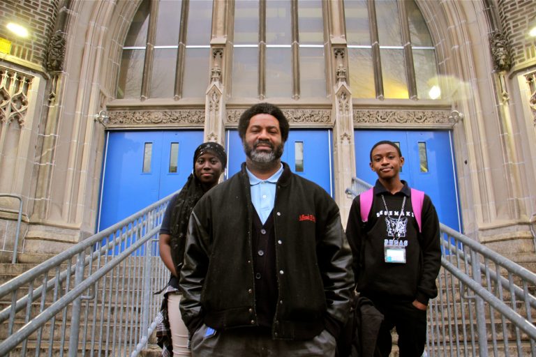 Mastery Shoemaker Principal Sharif El-Mekki, 46. stamds at the entrance to the school with students Essi Gasonu (left) and Bryce Thompson.  (Emma Lee/WHYY)