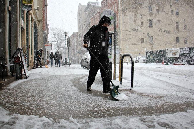 Shovelers clear snow in front of businesses on Third Street in Old City. (Emma Lee/WHYY)