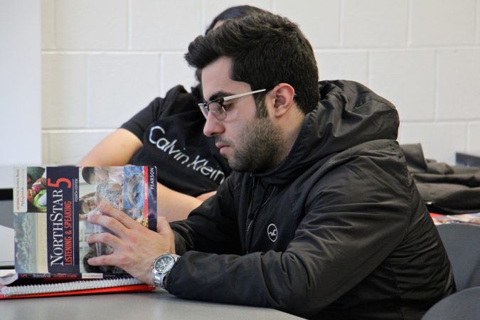 Ali Ashkanani of Kuwait opens his book during an intensive English class at Temple University. (Emma Lee/WHYY)