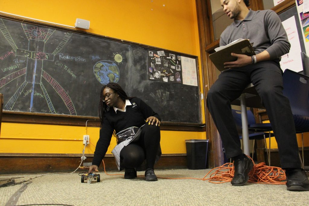 Christo Rey student Monica Kpedenou demonstrates her program for monitor Jared Boyd during a timed test.