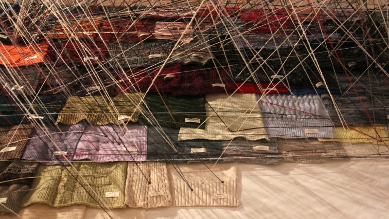 Donated sweaters are connected by threads in Jean Shin's 