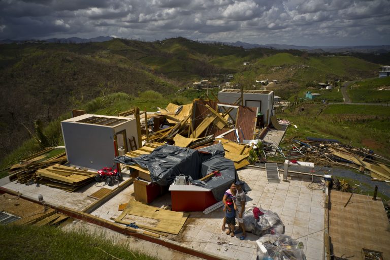 A family stand next to their belongings, in front of the remains of their home destroyed by Hurricane Maria, in the San Lorenzo neighborhood of Morovis, Puerto Rico, Saturday, Oct. 7, 2017. (Ramon Espinosa/AP Photo)