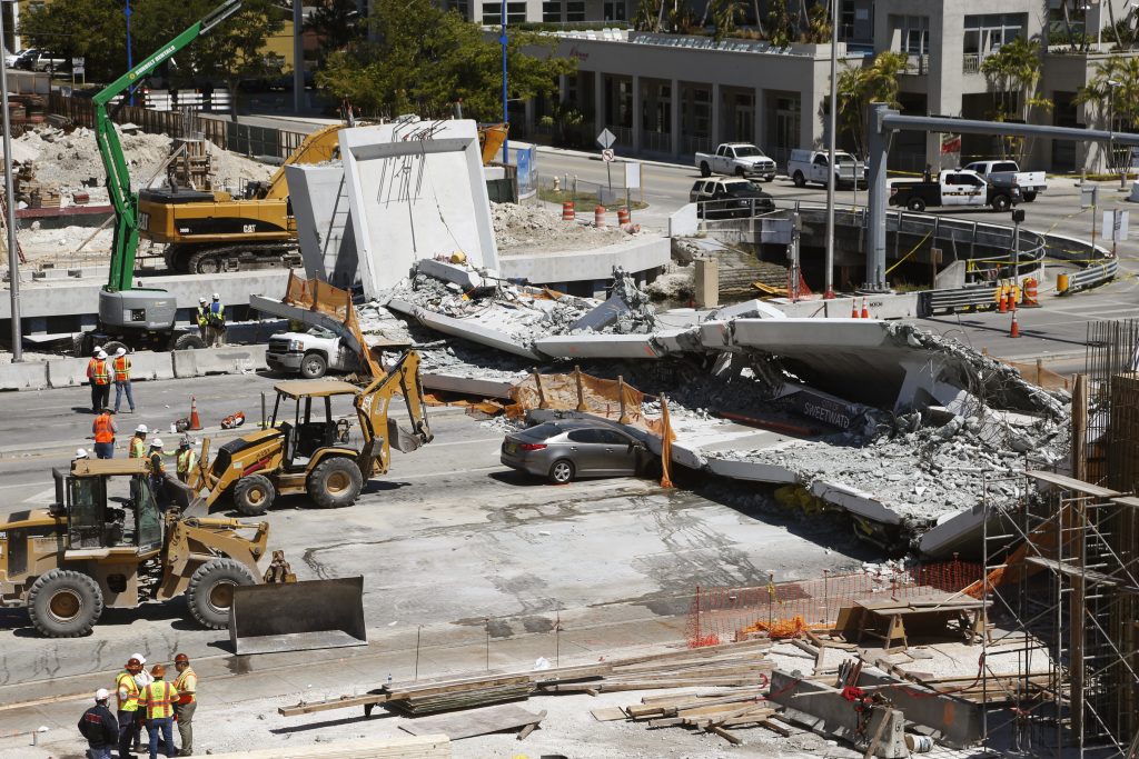 Crushed cars are shown under a section of a collapsed pedestrian bridge, Friday, March 16, 2018 near Florida International University in the Miami area. The new pedestrian bridge that was under construction collapsed onto a busy Miami highway Thursday afternoon, crushing vehicles beneath massive slabs of concrete and steel, killing and injuring several people, authorities said. (Wilfredo Lee/AP Photo)