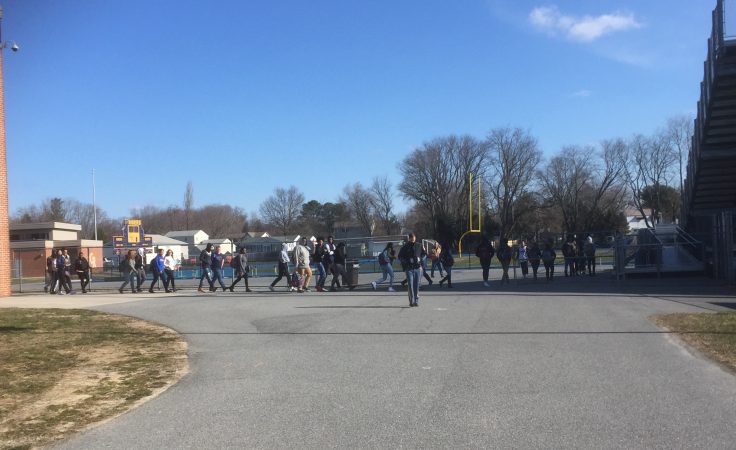 Students walking towards football field bleachers at Caesar Rodney High School in Dover.