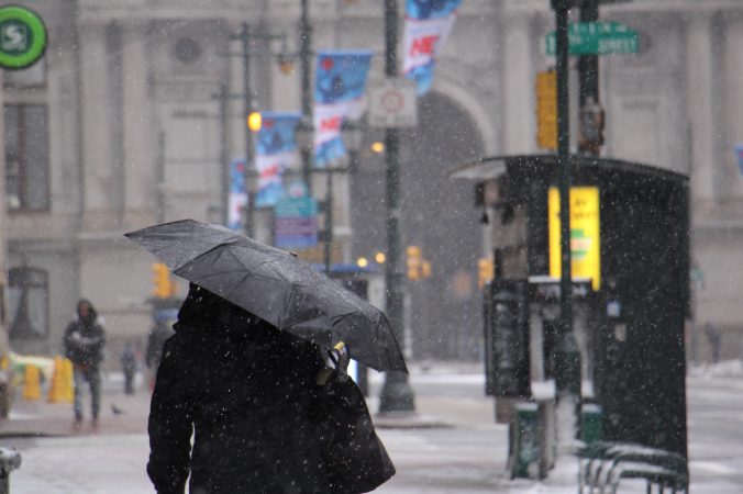 Umbrellas go up on Market Street near City Hall as the snow intensifies. (Emma Lee/WHYY)