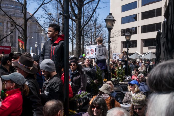 Demonstrators flood the streets of downtown Wahshington D.C. while others take a break at a restaurant during the March for Our Lives Saturday. (Brad Larrison for WHYY)