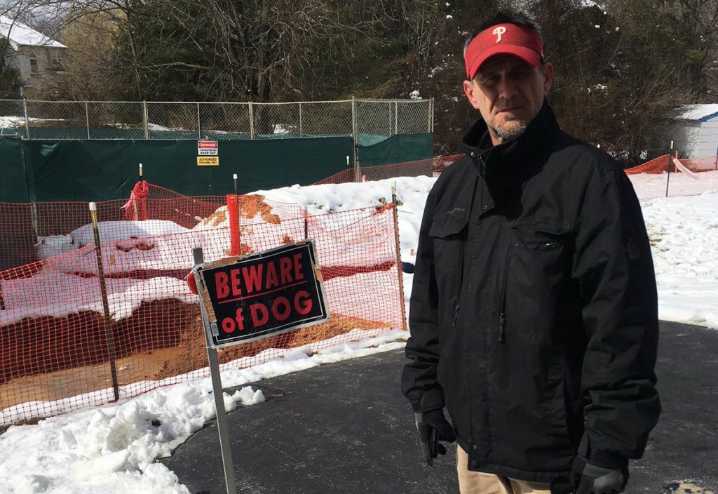 T.J. Allen, a resident of West Whiteland Township in Chester County, stands in front of sinkhole enclosures in his back yard. Allen said he's worried about the sinkholes, and the fact that Sunoco has been ordered to make sure an existing pipeline that runs through his neighborhood is safe. (Jon Hurdle/StateImpact Pennsylvania)
