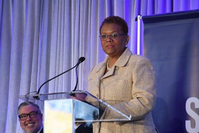 Screen Shot 2018-03-14 at 12.14.34 PM Della Clark speaks at a podium.