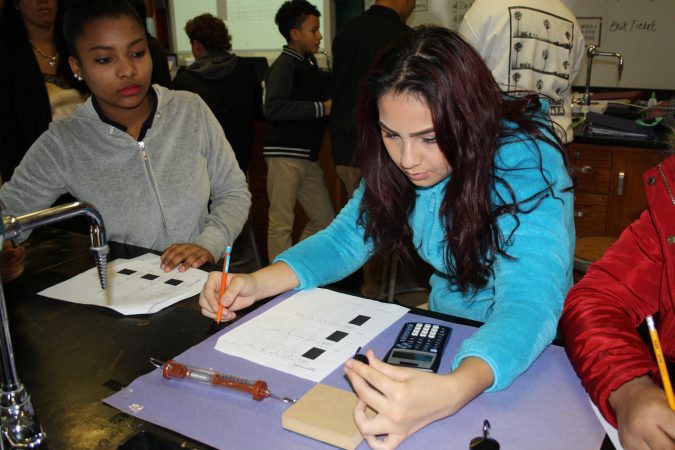 Maria Ramirez, left, and Eunice Millán, both freshmen at Woodrow Wilson High School in Camden, New Jersey, are taking physics this year as part of a “Physics First” initiative to prepare more students for STEM careers. (Tara García Mathewson/The Hechinger Report)