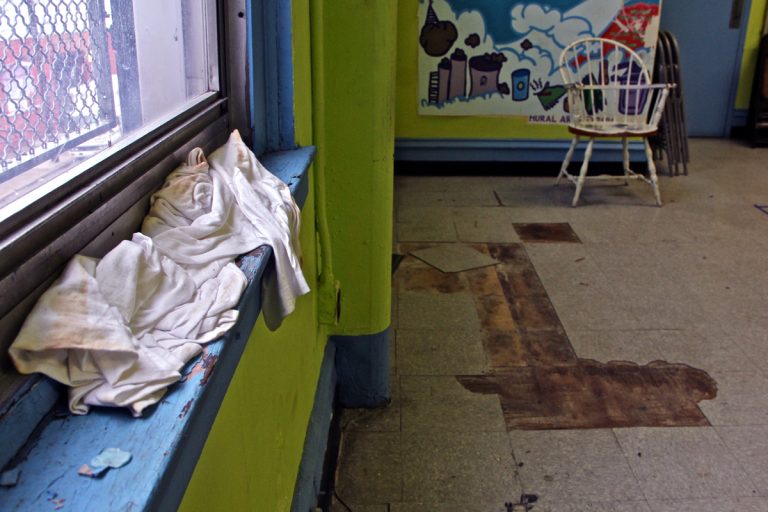 A T-shirt catches the drip from a leaking window frame in a multi-purpose room used by children at Vare Recreation Center in Grays Ferry. The 100-year-old building is badly in need of maintenance. (Emma Lee/WHYY)